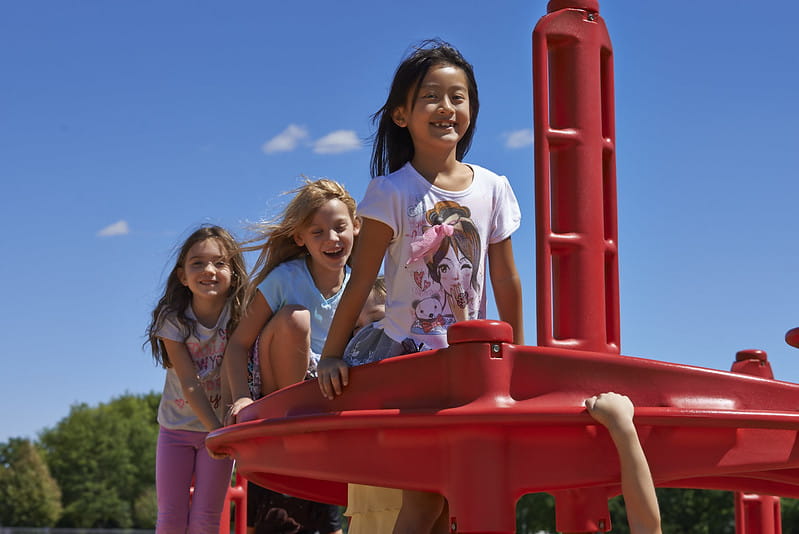 Three girls sitting and laughing on playground structure
